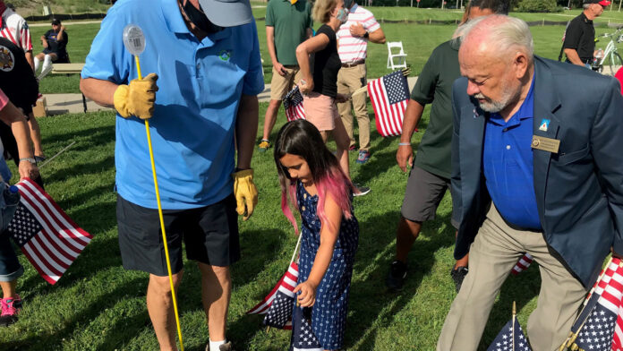 Volunteers place flags for the annual Field of Flags.