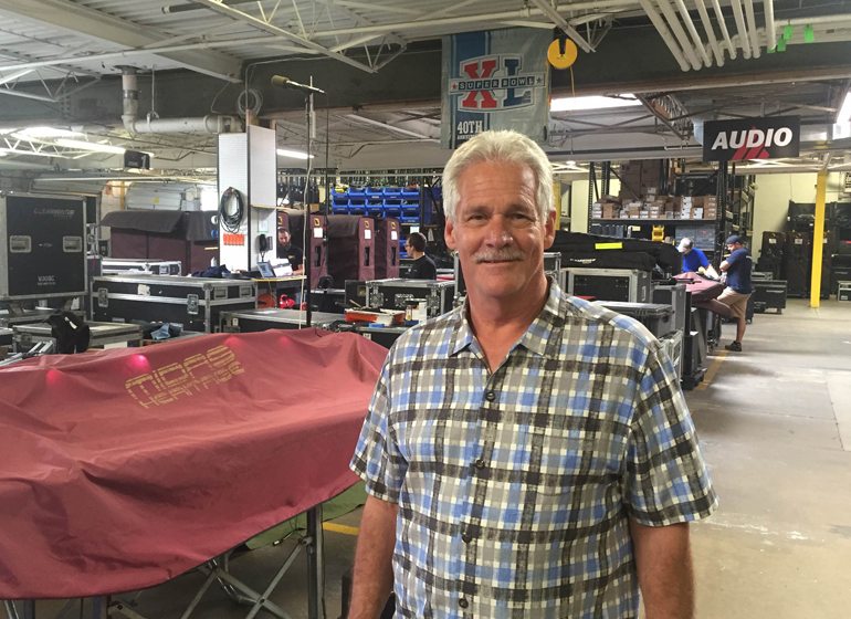 Clearwing Productions president and CEO Gregg Brunclik checks out the capabilities of a new light system and stands before rows of stage equipment at Clearwing’s West Allis warehouse.