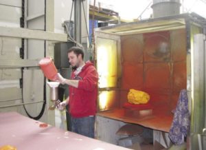 An employee at Foamation Inc. in St. Francis prepares to dye a buffalo chicken hat.