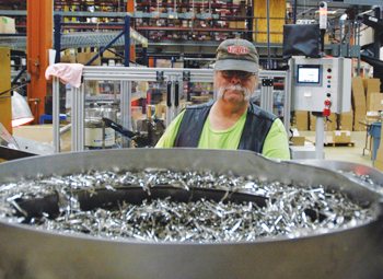 ibMilwaukee employee Timothy Adorjan operates a machine that attaches clips to pens at the company’s West Allis facility.