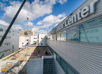 An installation crew lowers a massive cylindrical tube, part of the MR-linac system, into Froedtert & the Medical College of Wisconsin’s Clinical Cancer Center.