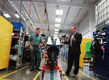 Erik Buell and Bill Melvin, Jr. roll the first motorcycle off the assembly line at EBR Motorcycles.